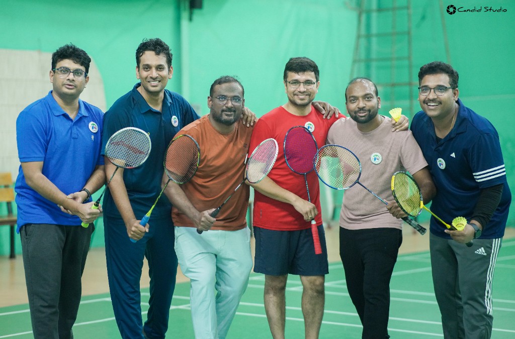 Six players with badminton rackets on an indoor court